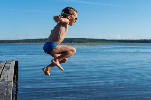 Young Caucasian woman  running on pier and diving into the lake