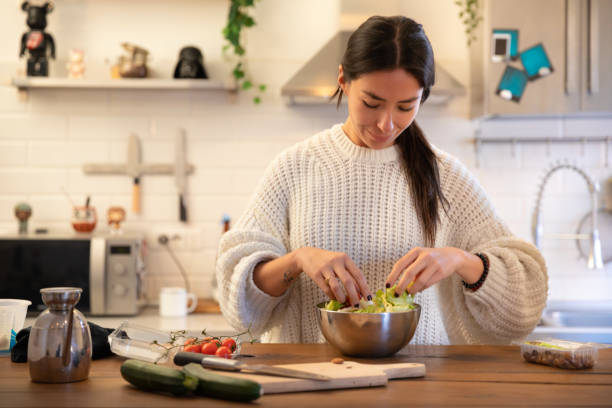 istock Beautiful Women Preparing A Salad In The Kitchen 1302663908