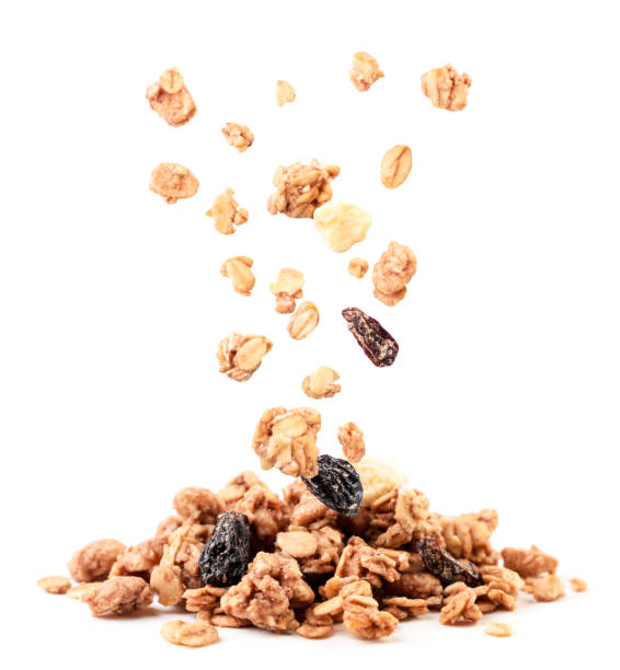 Crispy granola with raisins and banana falling on a heap on a white background. Isolated