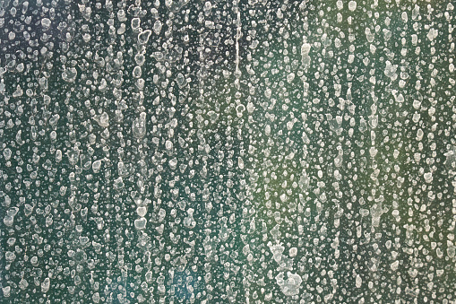 Rain water drops on glass turned into limescale; color photo.