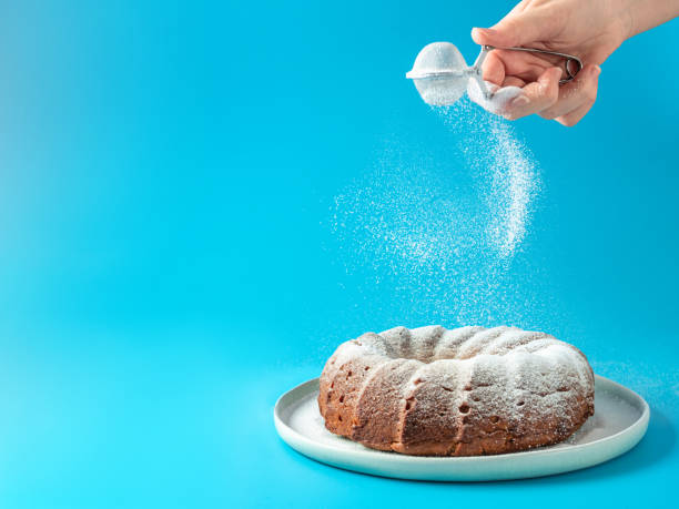 istock Female hand sprinkling icing sugar on bundt cake 1302666578