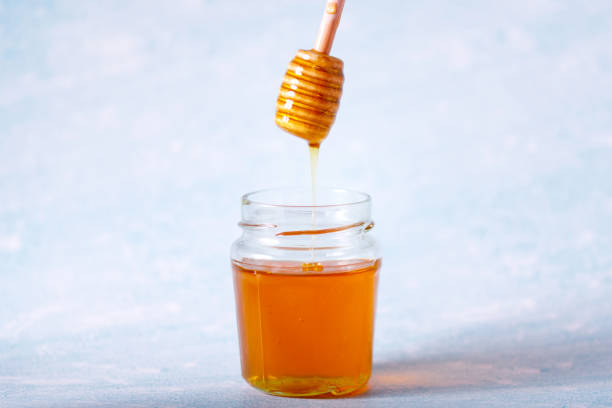 istock Honey dipper and fragrant honey falling into a bowl 1302666767