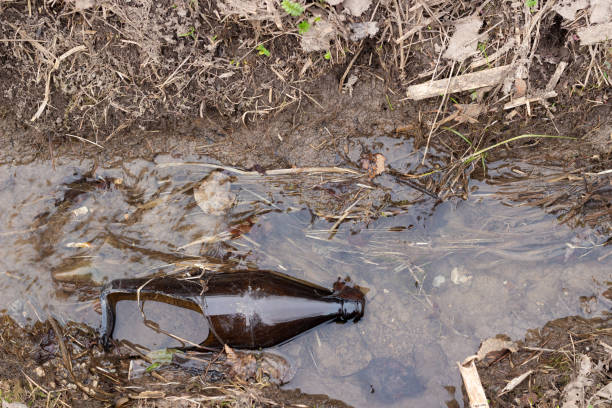 istock Broken glass bottle in a stream. Environmental pollution with consumer waste. Ecological disaster. 1302667920