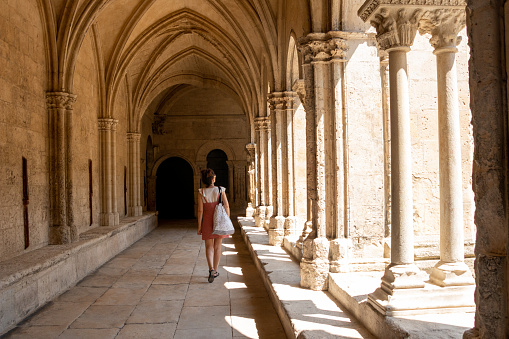 Young tourist woman visiting the cloister of the cathedral of Arles, France, in summer