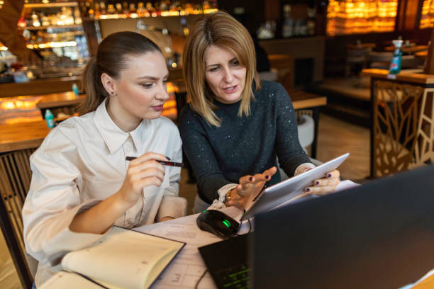 istock Two businesswoman sitting in cafe and talking about project while looking at digital tablet 1302670586