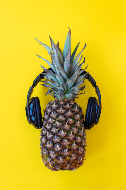 istock Pineapple in headphones on yellow background 1302670824