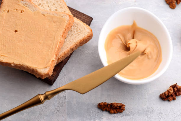 istock White bowl with natural walnut paste, golden knife, walnut and toast sandwiches on a light background. Traditional vegetarian breakfast close up 1302671646