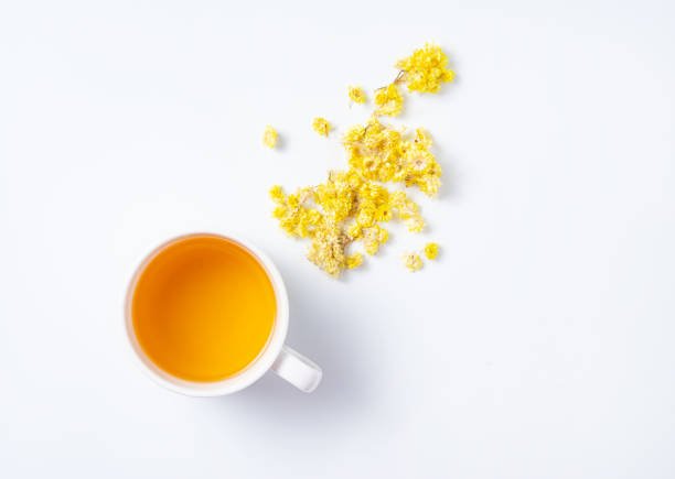 istock Fresh herbal tea with yellow flowers on a white background. Top view 1302675315