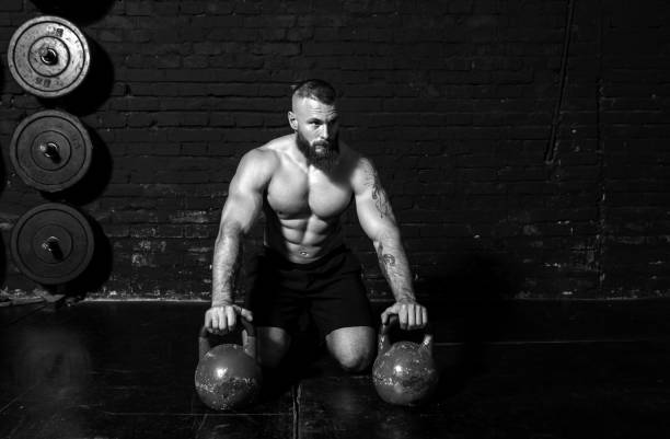 istock Young active sweaty strong muscular fit man with big muscles preparing for kettlebell workout in the gym as hardcore workout cross training real people exercise 1302676568