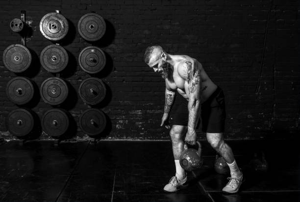 istock Young active sweaty strong muscular fit man with big muscles doing back shoulder muscle workout with one heavy kettlebell in the gym as hardcore cross training real people exercise 1302676569