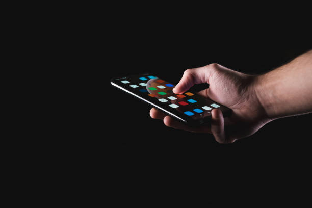 Male hand holding smartphone in black background