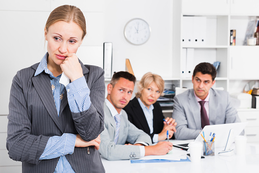 Business team tensely solving problems in office with upset woman foreground