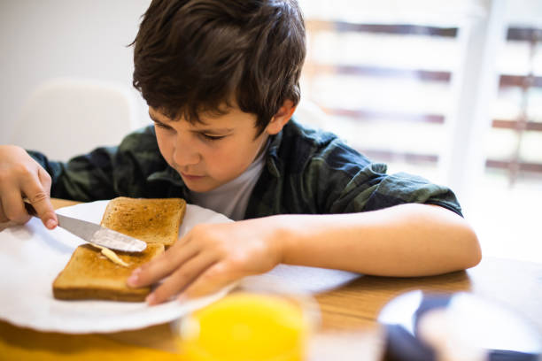 istock A cute boy spreading butter over a piece of toast 1302680098