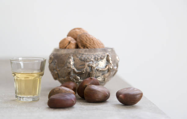 walnuts, chestnuts and a golden liquor glass on a concrete surface - whisky liqueur glass alcohol bottle imagens e fotografias de stock