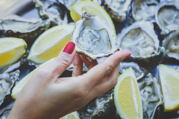 istock Hand holding fresh oyster over plate 1302682323