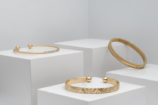 Three golden modern bracelets on white boxes