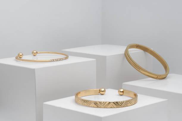 Three modern golden bracelets on white boxes with copy space Three golden modern bracelets on white boxes gold bangles pics stock pictures, royalty-free photos & images