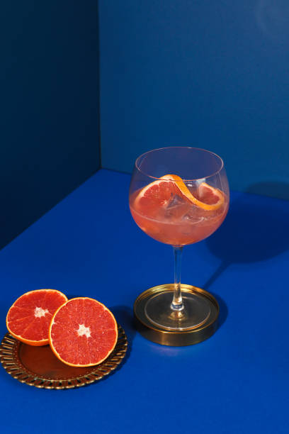 pop art style gin cóctel con fruta cítrica pomelo en fondo azul - mixing table fotografías e imágenes de stock