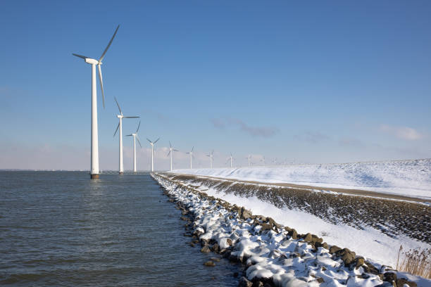 ligne au large des windturbines le long de la côte de ductch en hiver avec la neige - polder windmill space landscape photos et images de collection