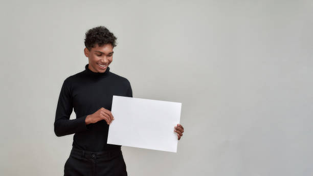 istock Smiling young african american man holding empty placard 1302689345