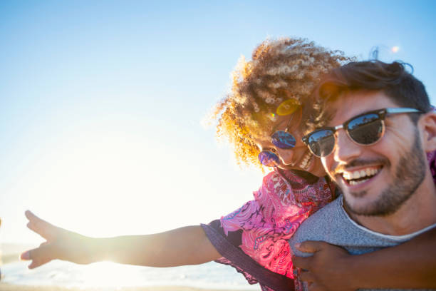 istock Multi ethnic Couples playing piggyback on the beach at sunset or sunrise. 1302689365