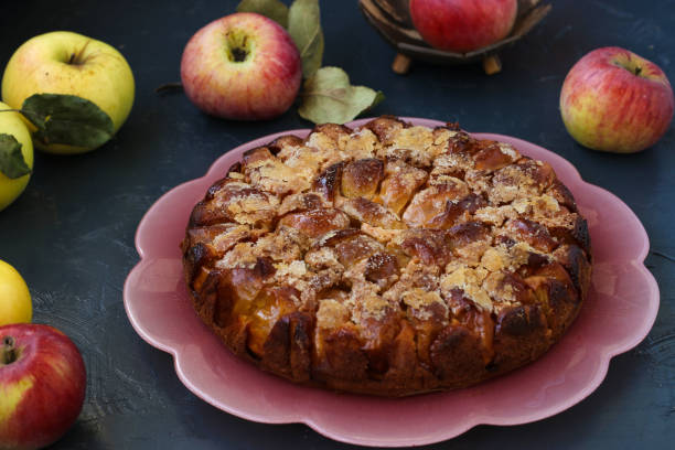 istock Homemade sugar pie with apples located on a dark background on a pink plate, horizontal orientation 1302689434