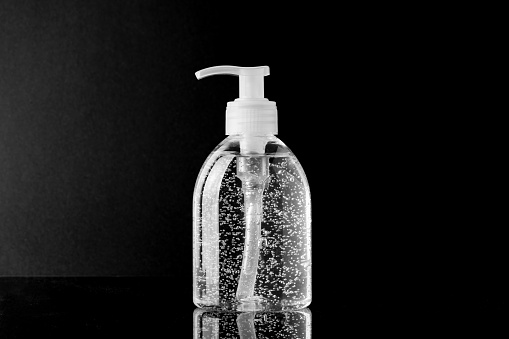 Detailed shot of a transparent hand sanitiser against black background with copy space