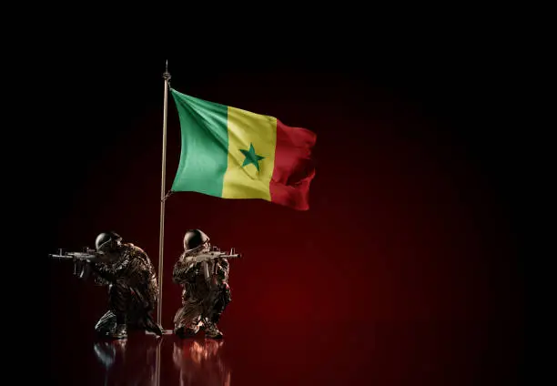 Concept of military conflict with soldier statues and waving national flag of Senegal. Illustration of coup idea. Two guards defending the symbol of country against red wall