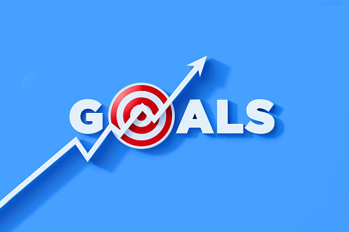 White line graph with arrowhead moving up over goals text and red bull's eye target on blue background. Horizontal composition with copy space. Goals, determination, strategy and motivation concept.