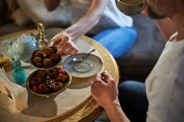 dżentelmen i pani cieszący się spokojnym wieczorem z herbatą i słodyczami - afternoon tea tea women table zdjęcia i obrazy z banku zdjęć