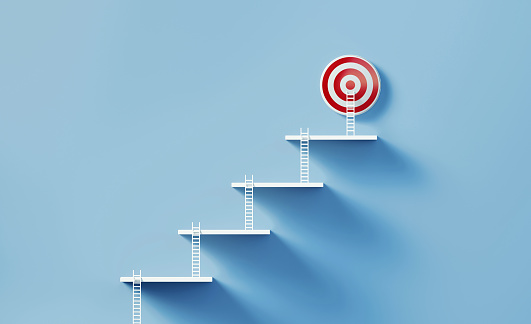 White ladders which leaning onto each other step by step reach a red bull's eye target on a blue wall.  Horizontal composition with copy space. Success and strategy concept.