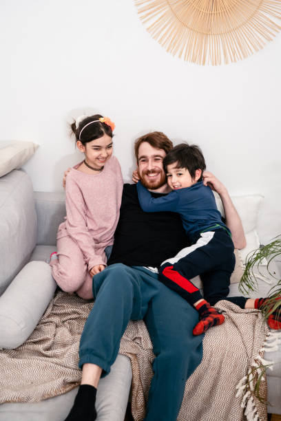 istock Father and two kids having fun on sofa at home 1302699498