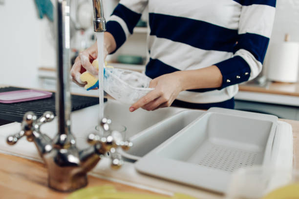 istock Unrecognizable girl washing a plastic lunch box 1302702387