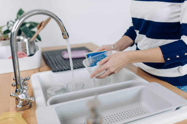 istock Unrecognizable young woman washing plastic dishes 1302702393