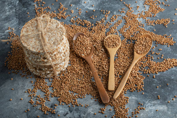 istock Stack of rice cakes and uncooked buckwheat on marble surface 1302705582