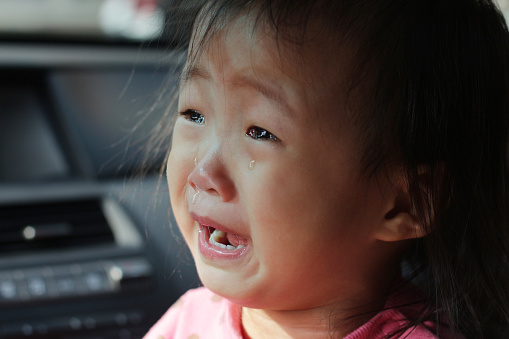 a Asian baby girl crying on her father's car.