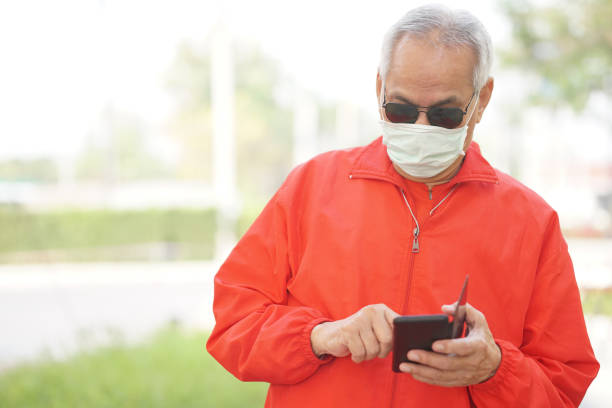 istock asian old elder senior man wearing face mask elderly using mobile smart phone cellphone. mature retirement lifestyle 1302708355