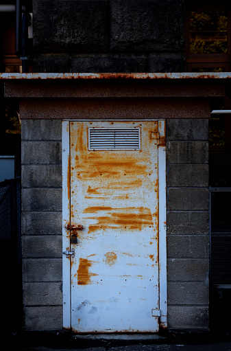 Dirty old rusty iron door with block wall warehouse.