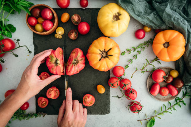 płaski leżał z rękami kobiet krojenie pomidory scheda i pomidory cherry - heirloom tomato organic tomato rustic zdjęcia i obrazy z banku zdjęć