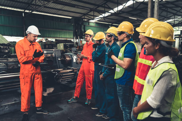 工場での短い会議に出席する熟練した労働者. - construction safety protective workwear hardhat ストックフォトと画像