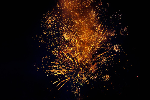 Colorful fireworks isolated on a dark background, close up, copy space. Bright yellow and gold sparks on a dark background. Can be used as a festive background