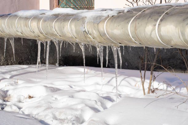 istock Very beautiful transparent icicles hanging from a snow-covered pipe. Spring melting snow 1302728423