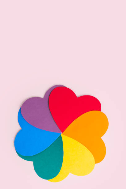 istock Multicolored paper hearts forming a flower shape with rainbow petals on a pink background, vertical frame 1302728449