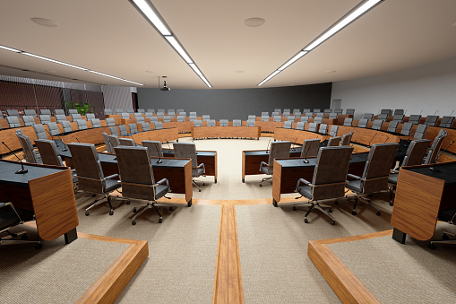 Interior Of An Empty Conference Hall With Gray Color Seats, Microphones On The Desks And Carpeted Flooring.