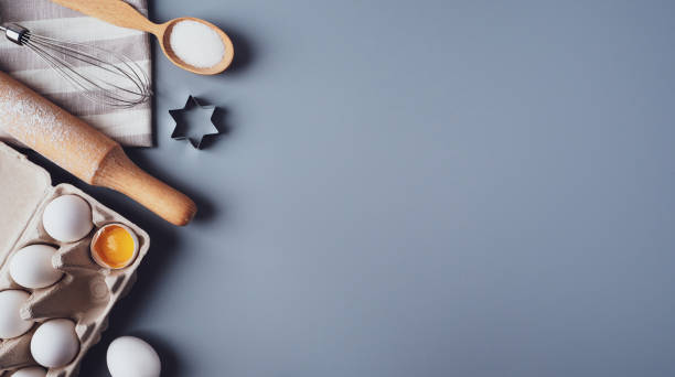 istock Different ingredients and kitchen utensils for making cookies or cupcakes, flat lay, copyspace. Eggs, rolling pin, whisk, flour, cookie molds, layout on a gray background. The concept of home baking 1302733836