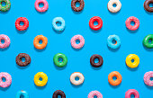 Multicolored donuts top view isolated on a blue background. Glazed doughnuts pattern.