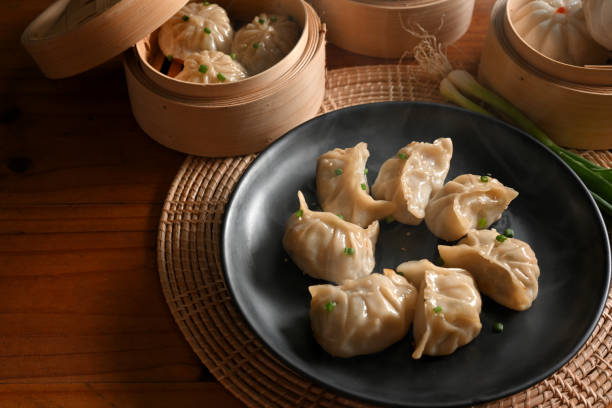 istock Kitchen table with a plate of dumplings and bamboo steamer 1302737363