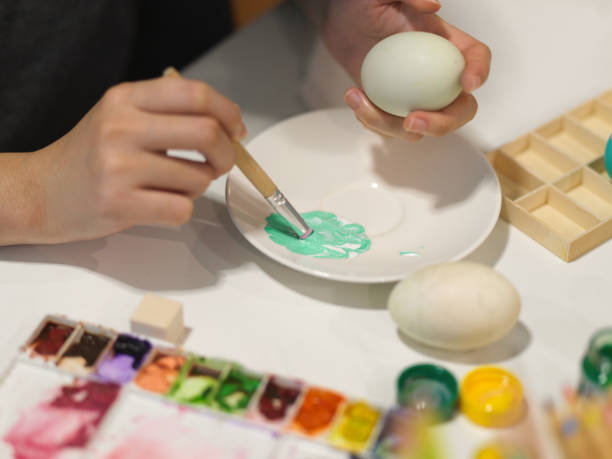 istock Hands painting egg with poster colour preparing for Easter festival 1302737410