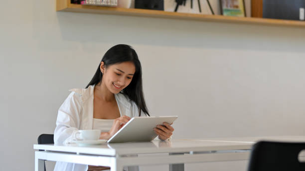 istock Portrait of female smiling while using digital tablet with stylus pen in cafe 1302737561