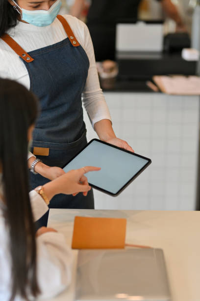 istock Female waitress with apron service her customer to ordering menu on digital tablet 1302737632